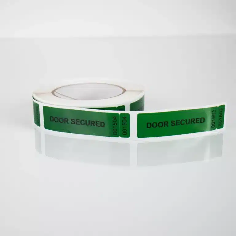 Image of a roll of green Tampertech tamper evident Door Secured non-residue label, 85mm x 25mm + 25mm x 10mm DNT, 1000 labels per roll.