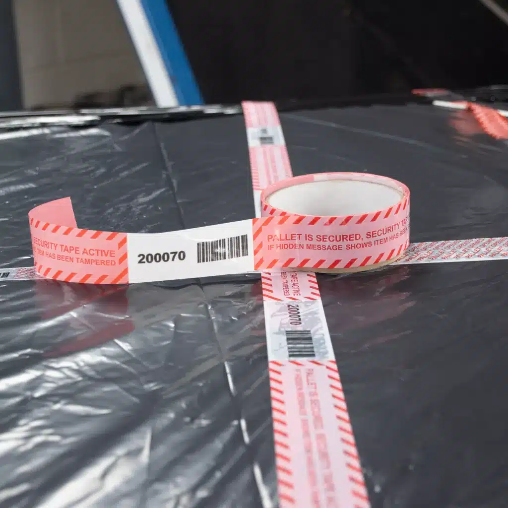 Close up image of Tampertech Pallet Secure Tamper Evident Security Tape applied, removed, demonstrating the tamper evident permanent void message left clearly on the pallet wrap with sequential number and matching barcode per roll, 30mm x 15m per roll.