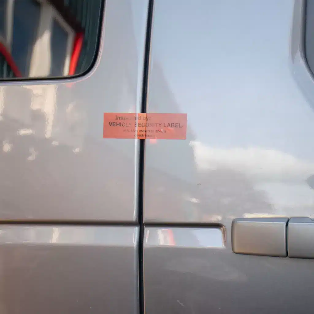 Red vehicle secure non-residue label from Tampertech applied to vehicle doors.