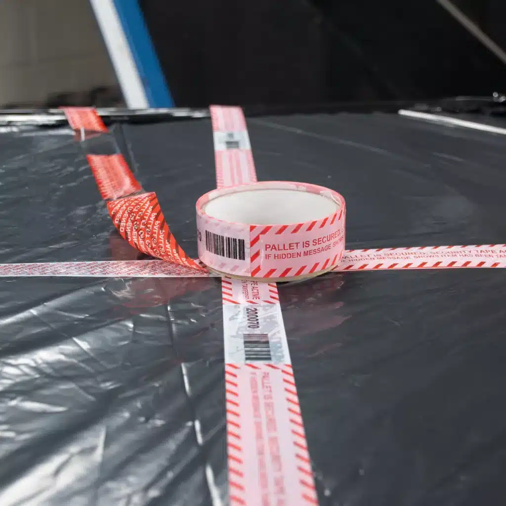 Image of Tampertech Pallet Secure Tamper Evident Security Tape roll, applied, removed, and void message on black pallet wrap.